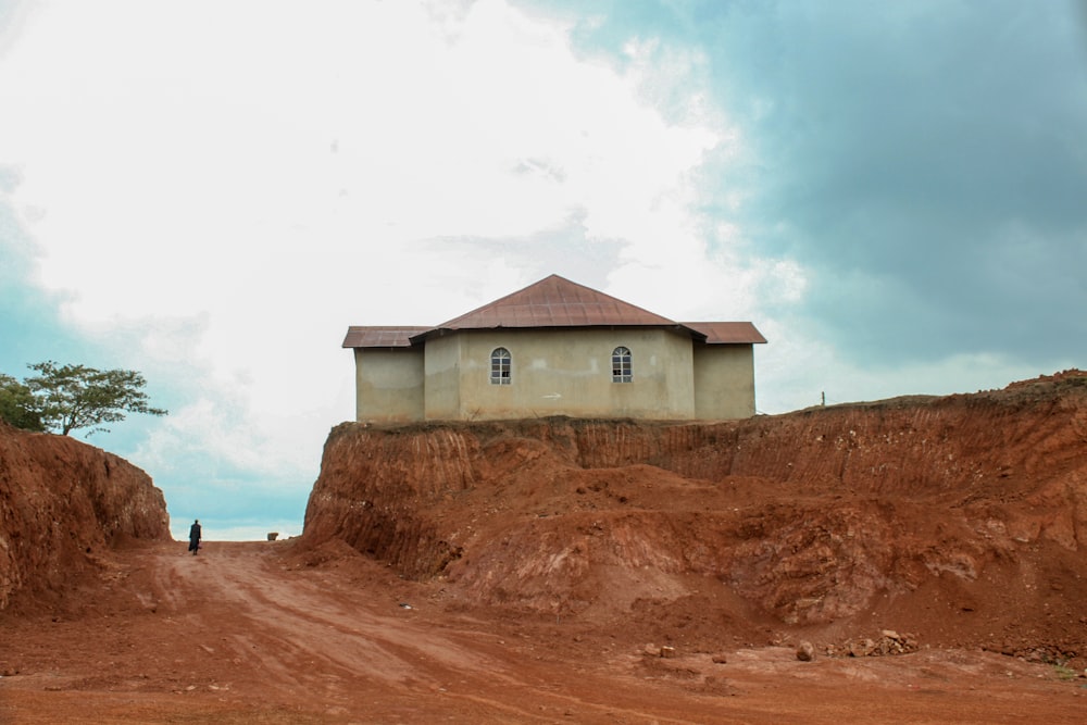 white and brown house on brown sand under white clouds during daytime