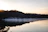 A serene lakeside view at sunrise with mist rolling over the hills, capturing the peaceful essence of a Sukoon Vihar trip.