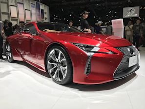 A sleek red sports car gleaming under showroom lights at a recent auto expo.