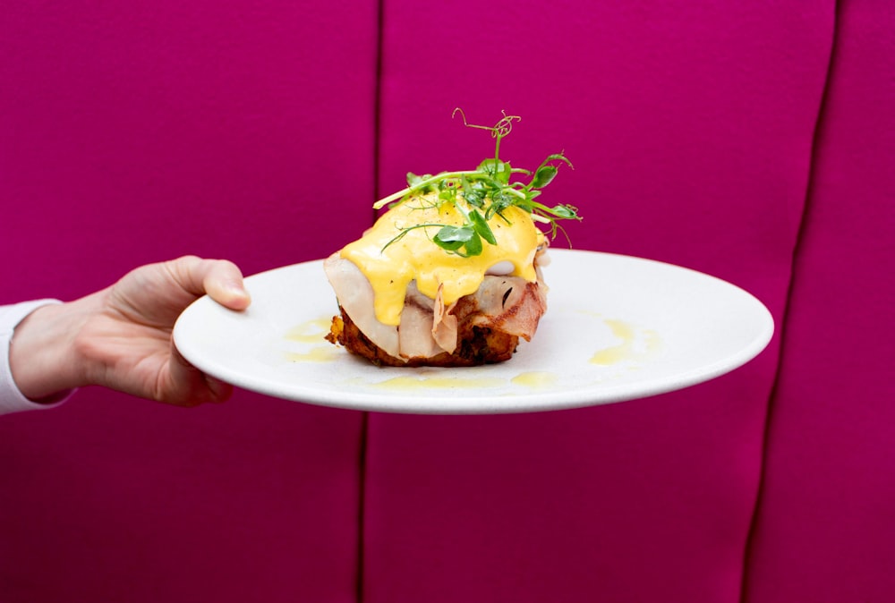 person holding white ceramic plate with burger