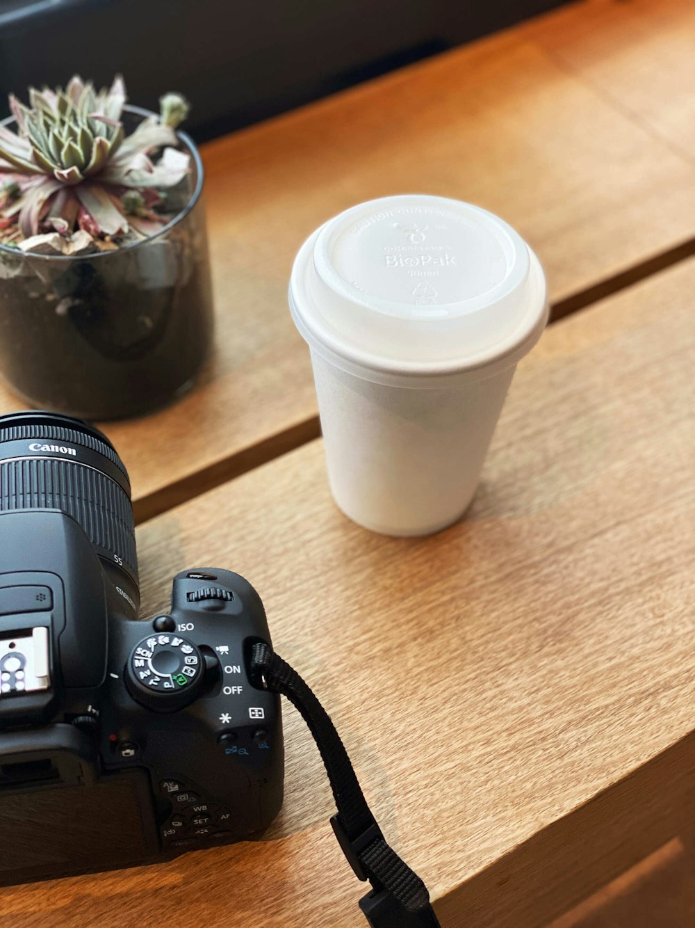 black nikon dslr camera beside white disposable cup