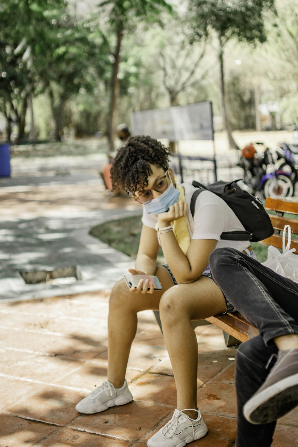 woman in white t-shirt sitting on brown wooden bench during daytime