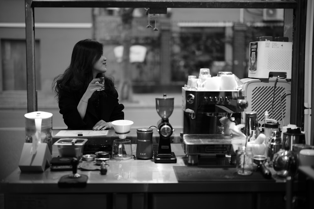 woman in black jacket sitting on chair in grayscale photography