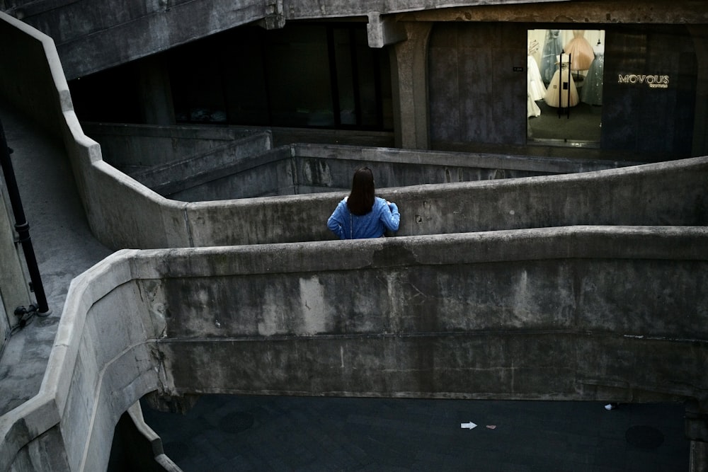 man in blue hoodie sitting on concrete stairs