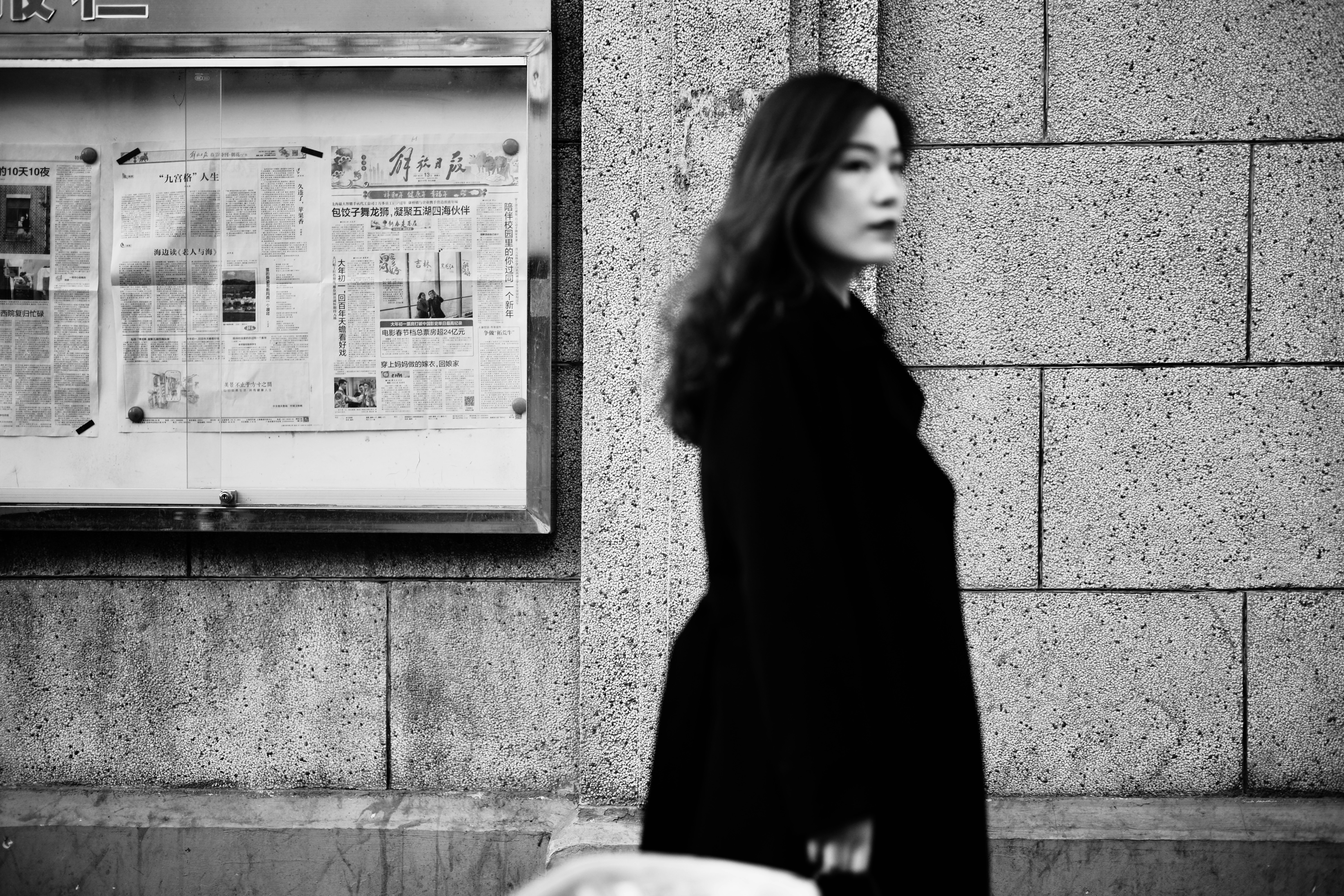 mulher no casaco preto de pé perto da parede