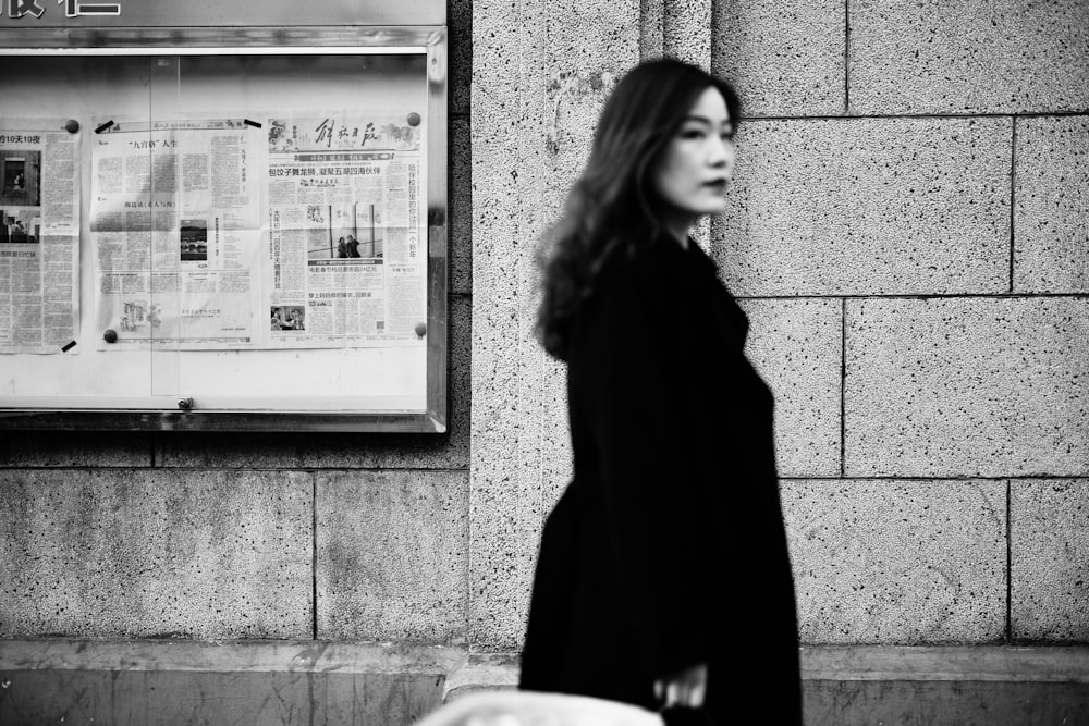 woman in black coat standing near wall