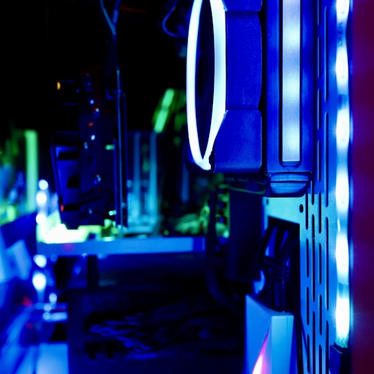 A close-up view of the internal components of a computer, featuring LED lights and cooling fans. The image is lit with blue and green hues, highlighting the sleek, modern design of the hardware.