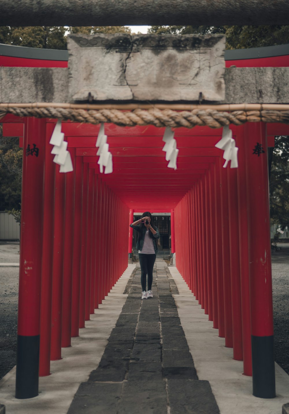 woman in black jacket and black pants standing on gray concrete pathway