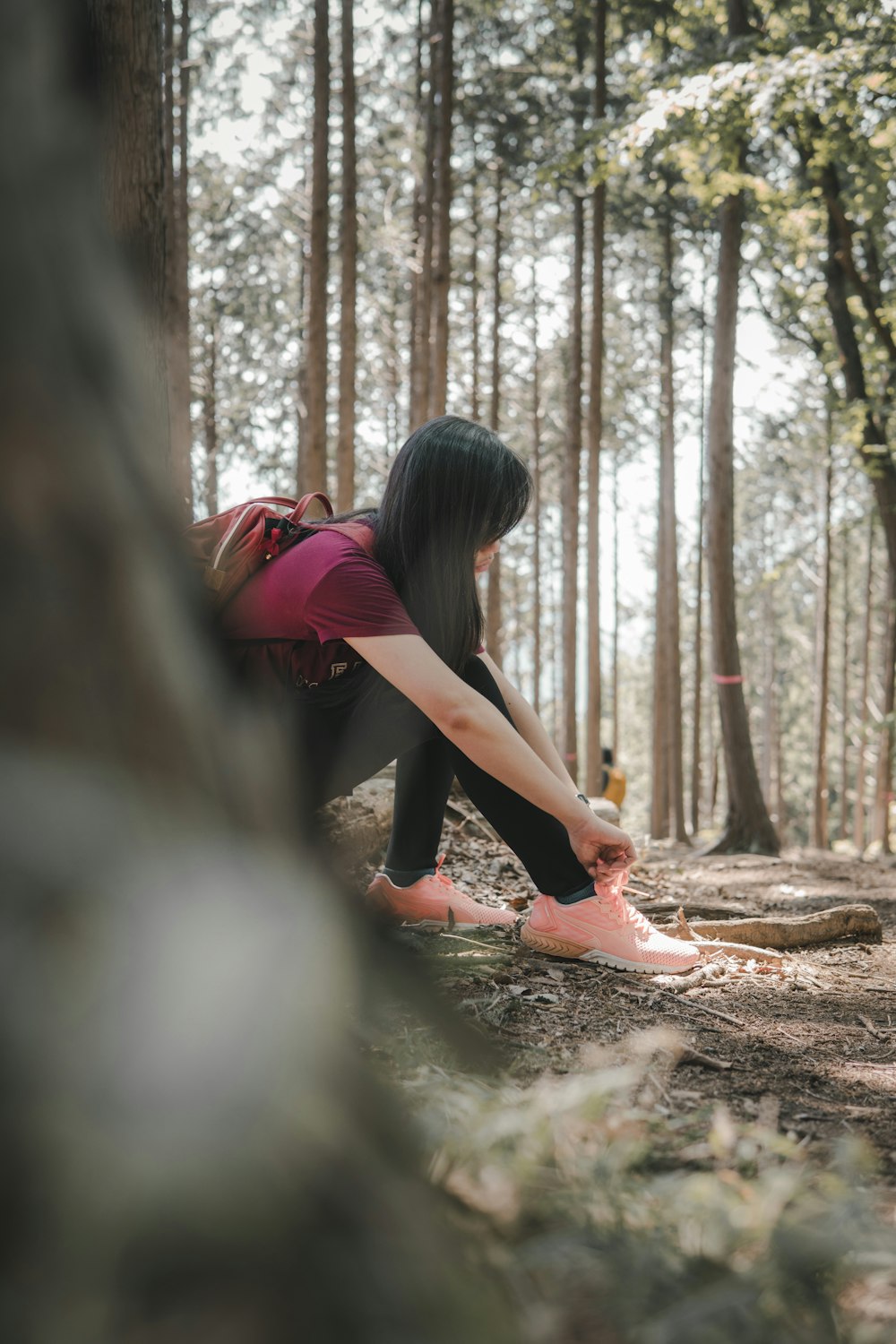 woman in red shirt and black pants standing on forest during daytime