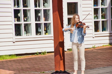 woman in white shirt and white pants standing beside brown wooden door during daytime