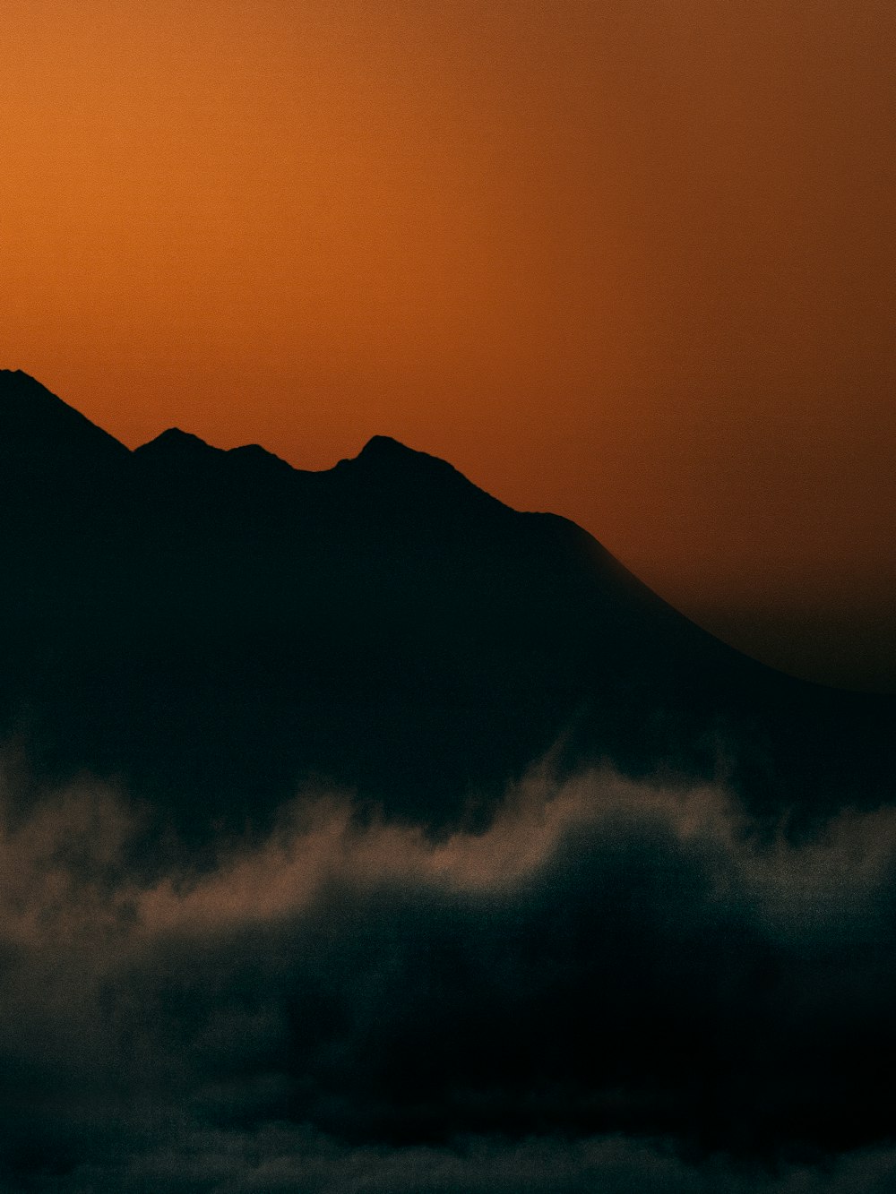 silhouette of mountain under cloudy sky during daytime