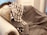 A plush, ornately carved sofa is draped with a patterned, brown and white checked blanket. A soft, floral-patterned pillow in gold hues complements the luxury of the setting.