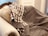 A plush, ornately carved sofa is draped with a patterned, brown and white checked blanket. A soft, floral-patterned pillow in gold hues complements the luxury of the setting.