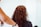 A person with curly brown hair is being attended to, possibly in a salon environment. The arm of another individual is visible, suggesting hair styling or cutting.