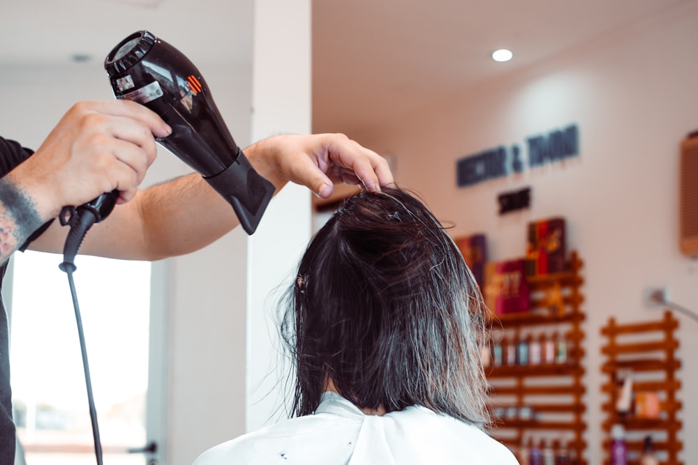 woman in white shirt holding hair blower