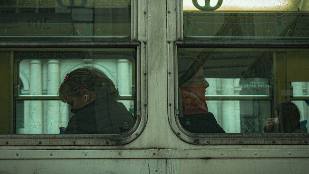 man in red jacket standing in front of train window