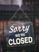 a closed sign hanging on a mesh fence