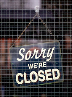 a closed sign hanging on a mesh fence