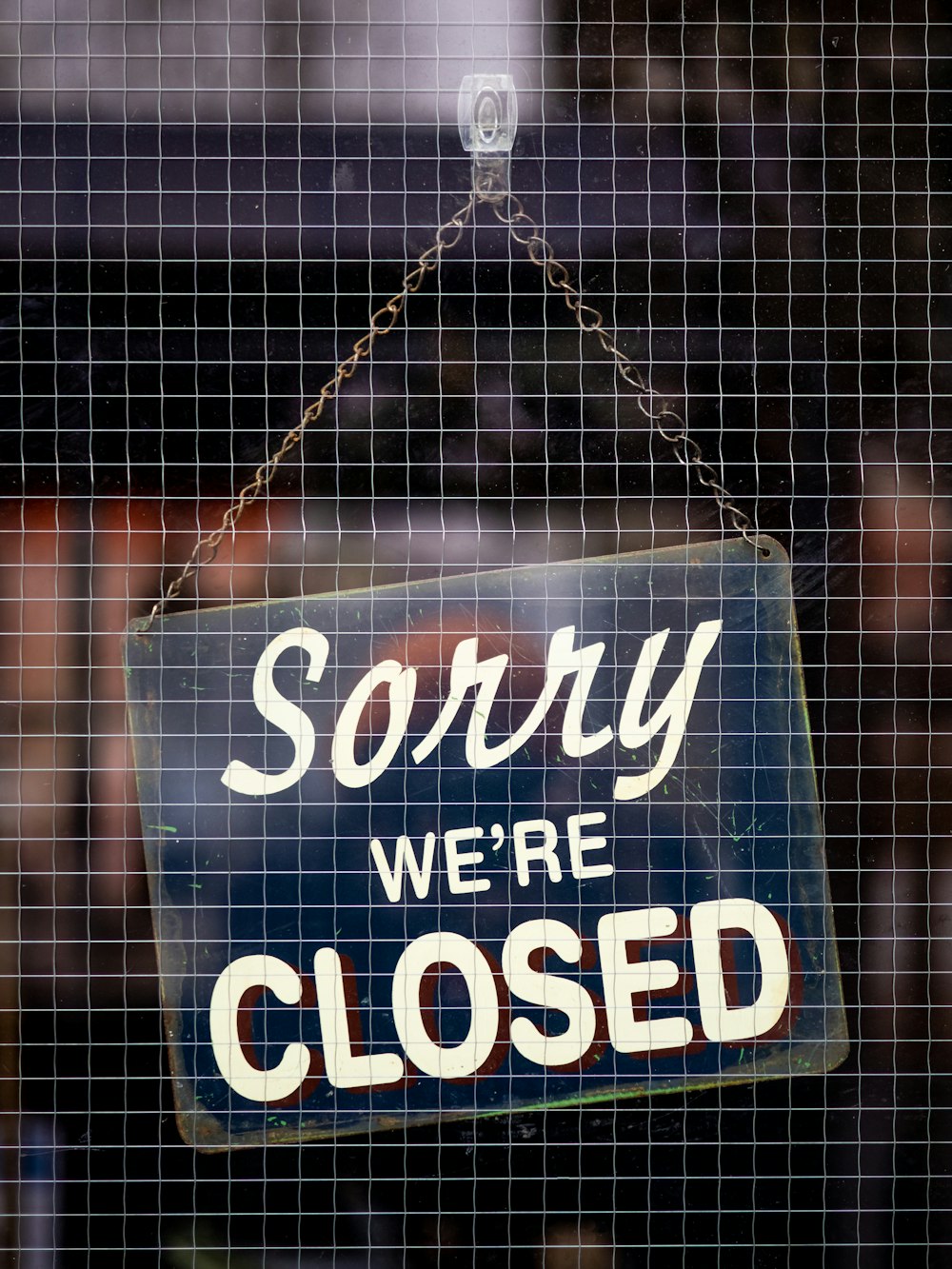 a closed sign hanging on a mesh fence