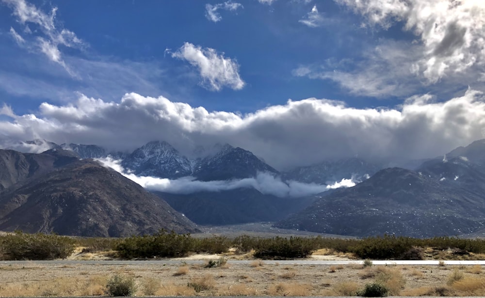 campo de grama verde perto da montanha sob o céu azul durante o dia