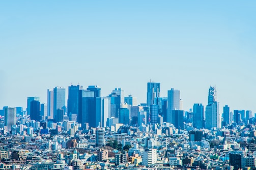 A panoramic city skyline view highlighting urban rooftops and modern high-rises under a clear blue sky.