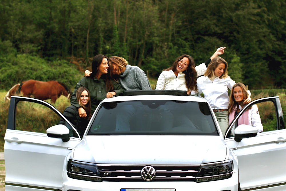 group of people standing beside white car during daytime