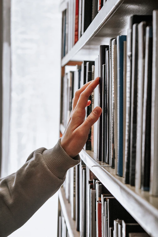 hand reaching for books on shelf
