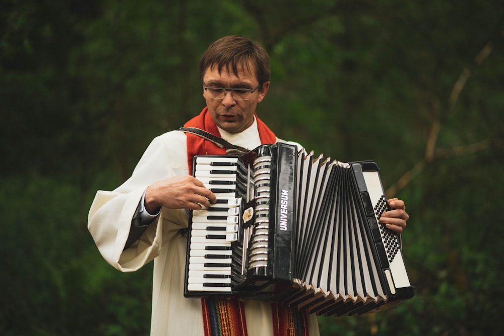 man in white and red collared shirt playing black and white accordion