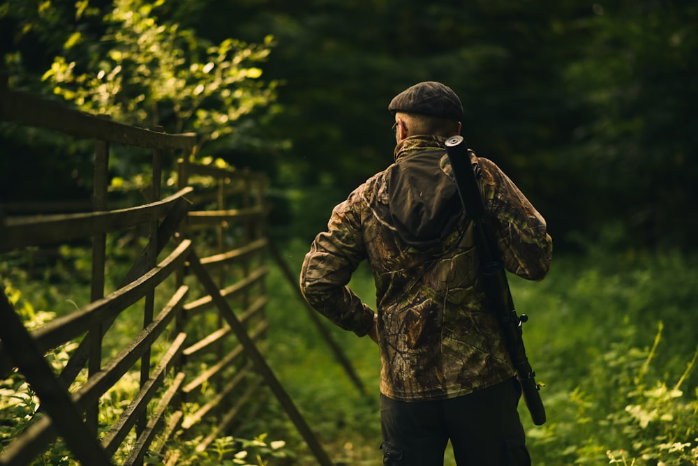 man in brown jacket standing on wooden bridge