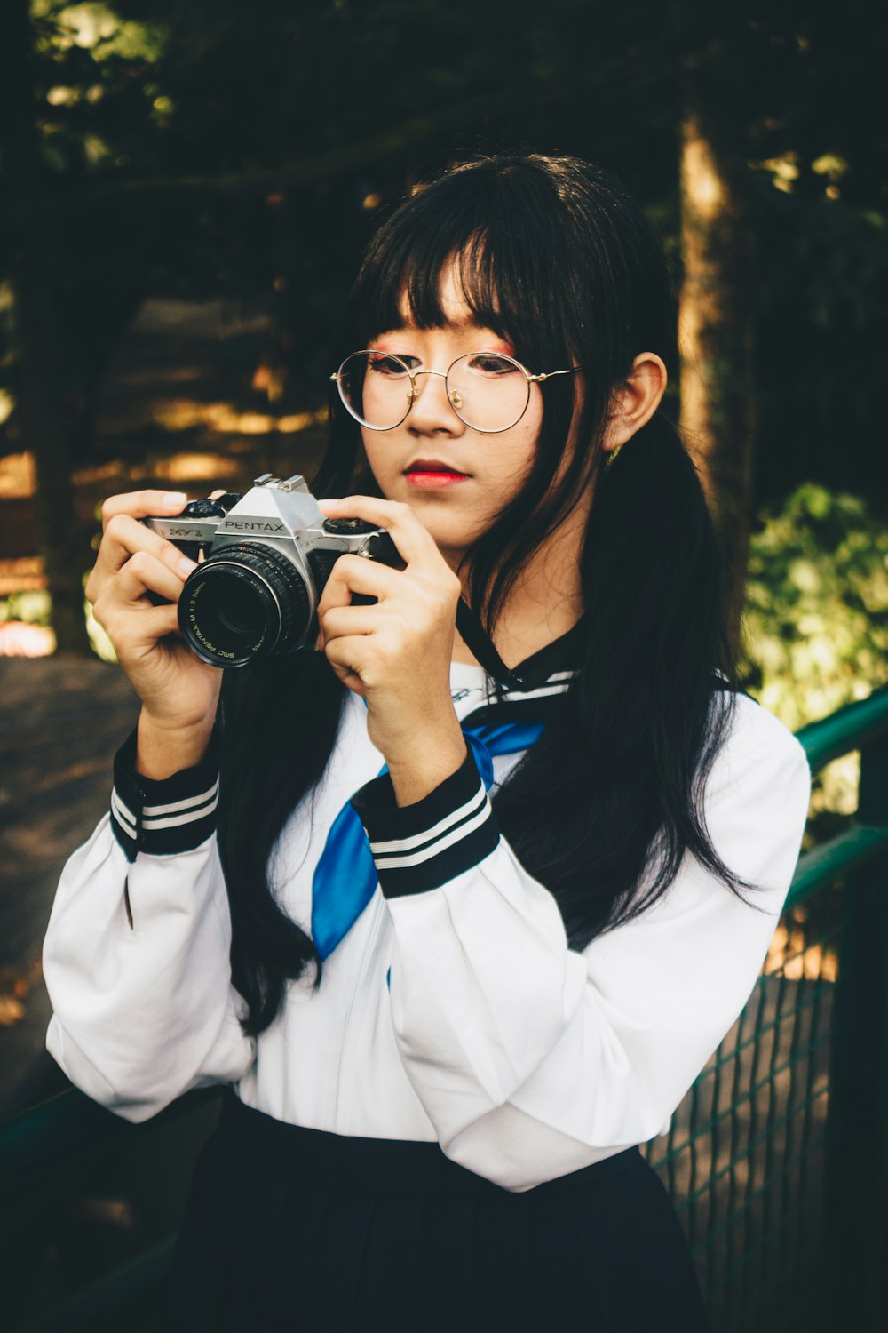 a woman with glasses taking a picture with a camera