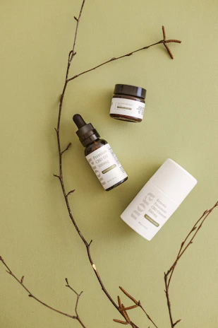 A serene flat lay of natural skincare products with burgundy and olive accents on a wooden table.