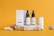 A collection of skincare products is displayed on a textured stone platform against a vibrant orange background. The items include two brown dropper bottles labeled 'Premium CBD Oil' and a white box labeled 'Acne Treatment CBD Cream.' Additional bottles and textured stones are arranged artistically around the platform.