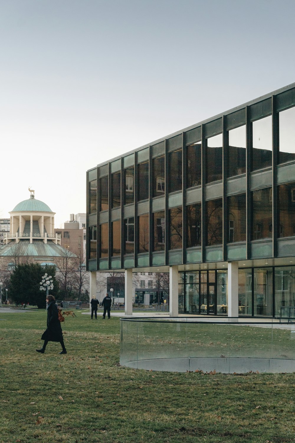 man in black coat walking on green grass field near brown concrete building during daytime