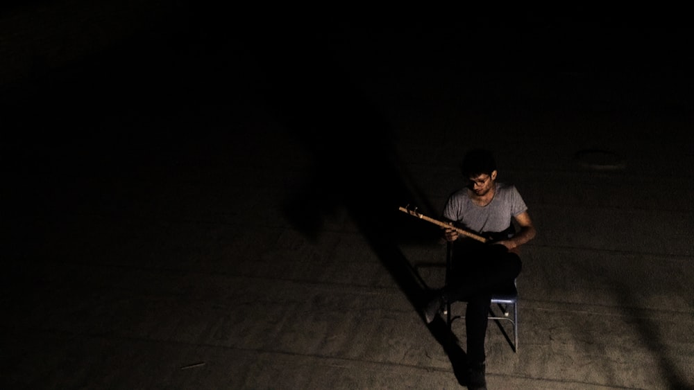 Hombre con camiseta gris de cuello redondo tocando la guitarra