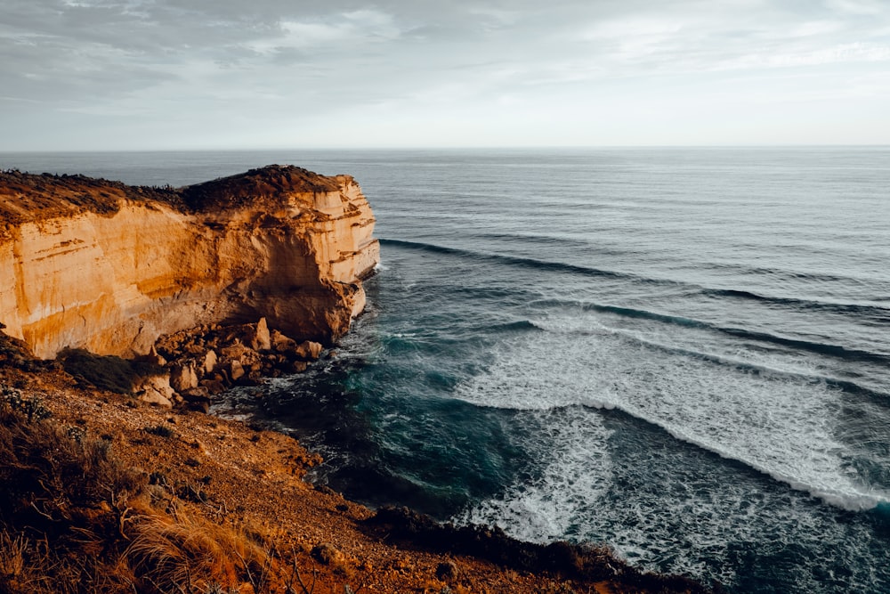 brown rock formation beside body of water during daytime