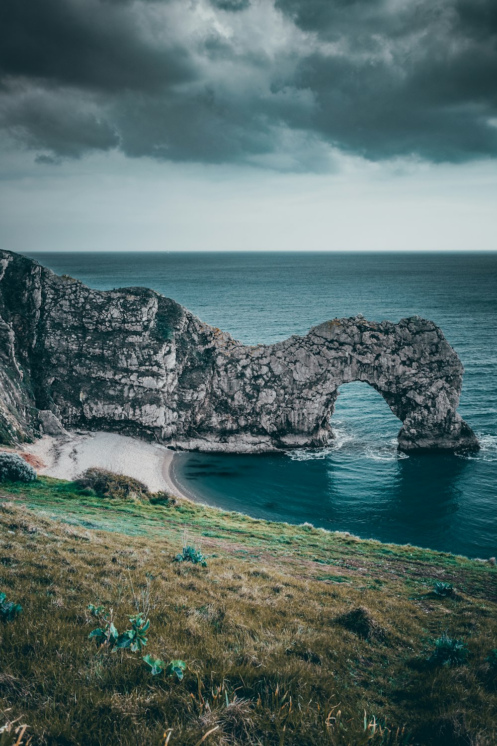 gray rocky mountain beside body of water under white cloudy sky during daytime