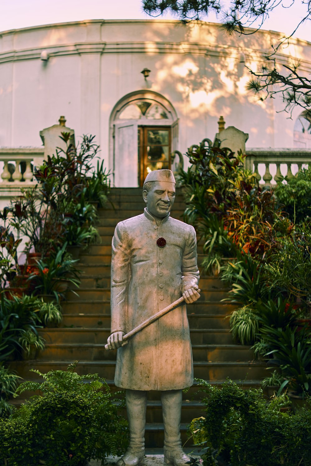 man holding stick statue near green plants during daytime