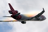 white and red airplane under white clouds during daytime