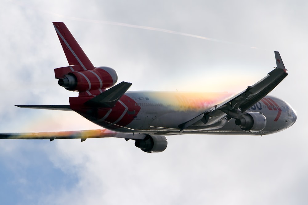 white and red airplane under white clouds during daytime