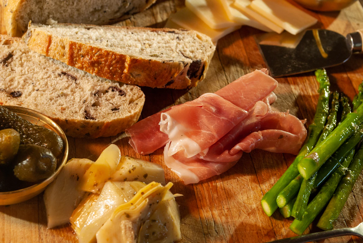 An antipasto board of cured meats, cheeses and bread, shot from above.