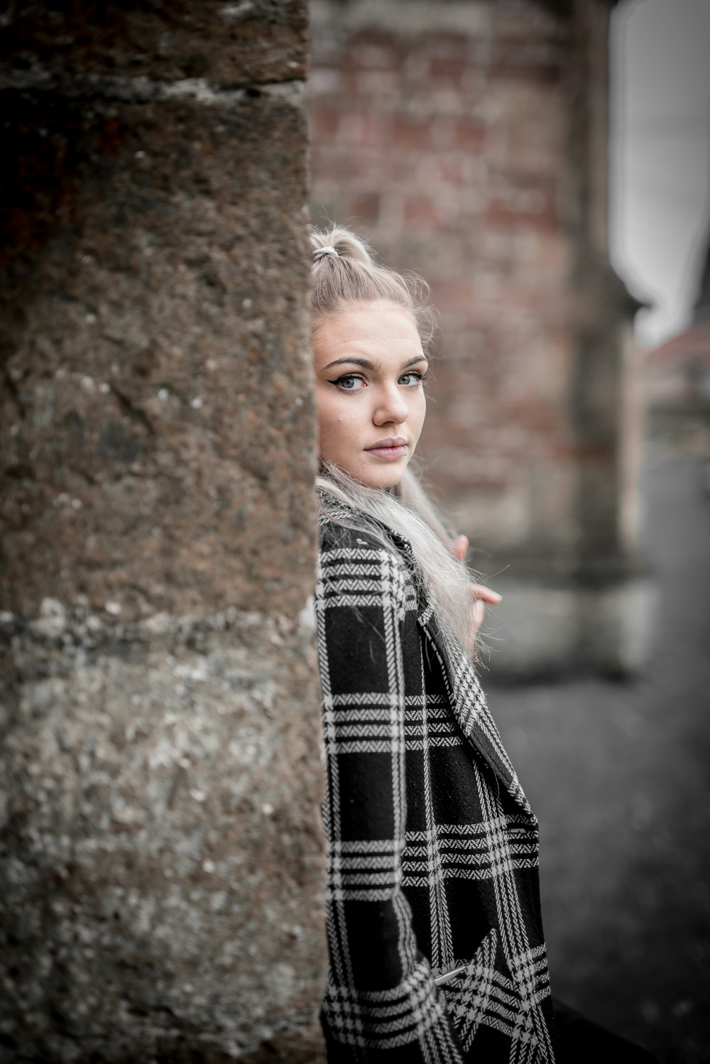 woman in black and white plaid scarf standing beside brown tree