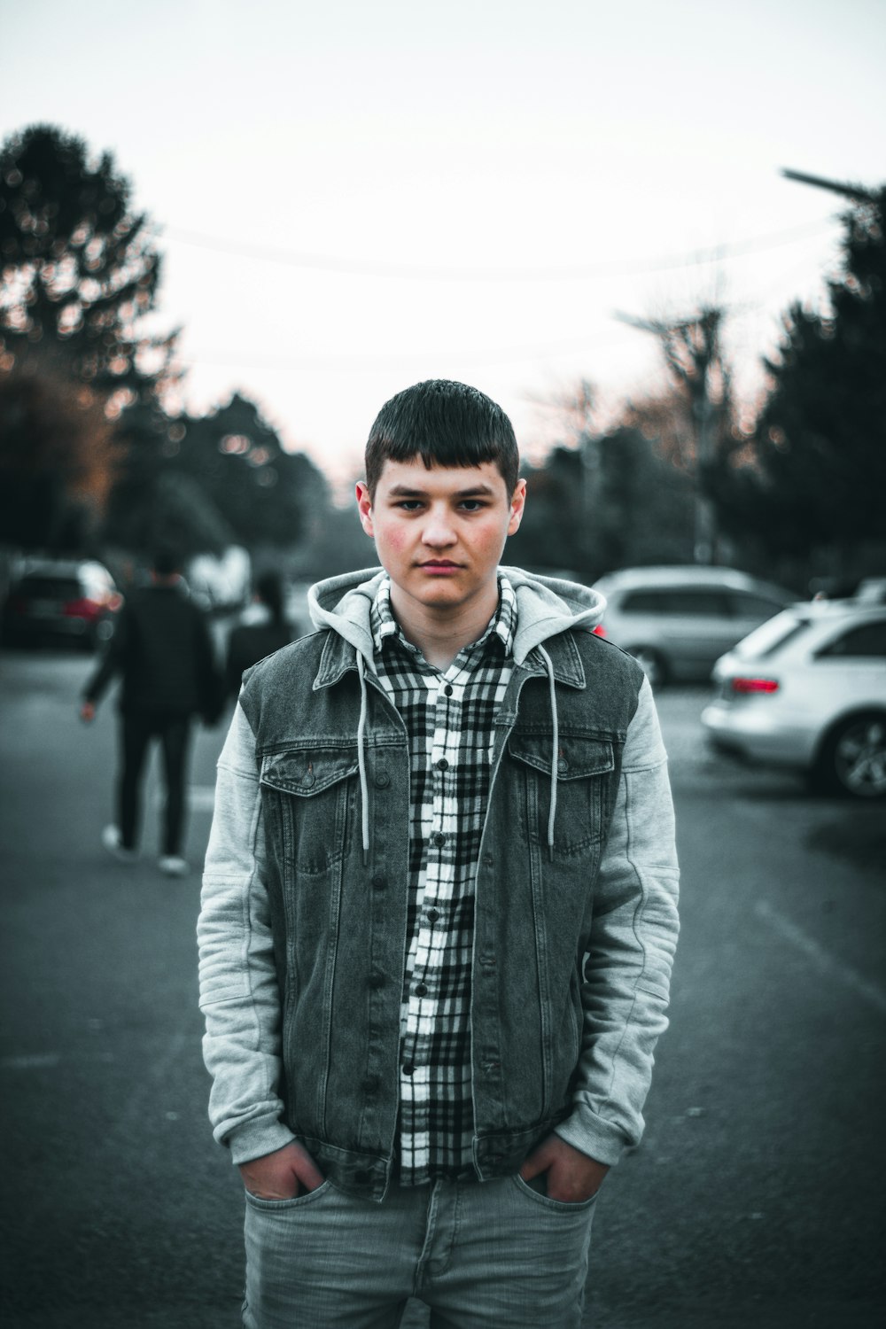 man in gray zip up jacket standing on road during daytime