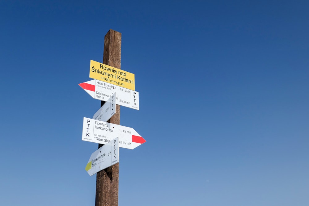 white and brown wooden street sign under blue sky during daytime