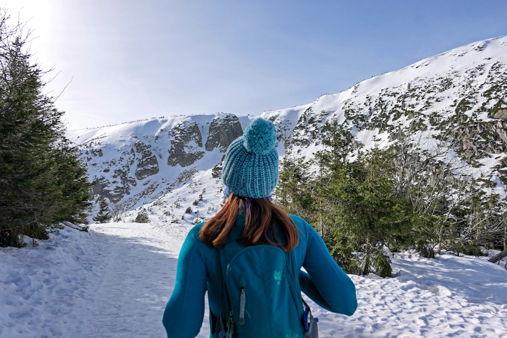 woman in blue jacket and gray knit cap standing on snow covered ground during daytime