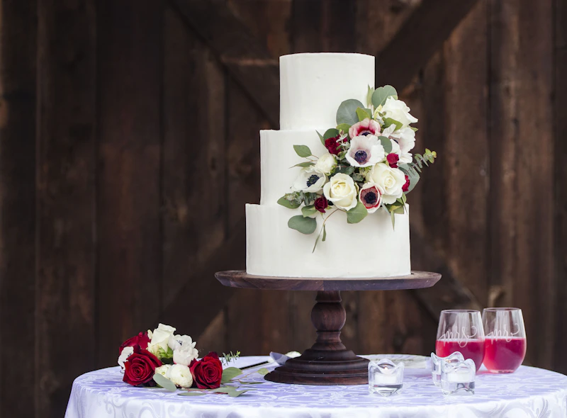 Three-tier white celebration cake with a cascading arrangement of red and white flowers