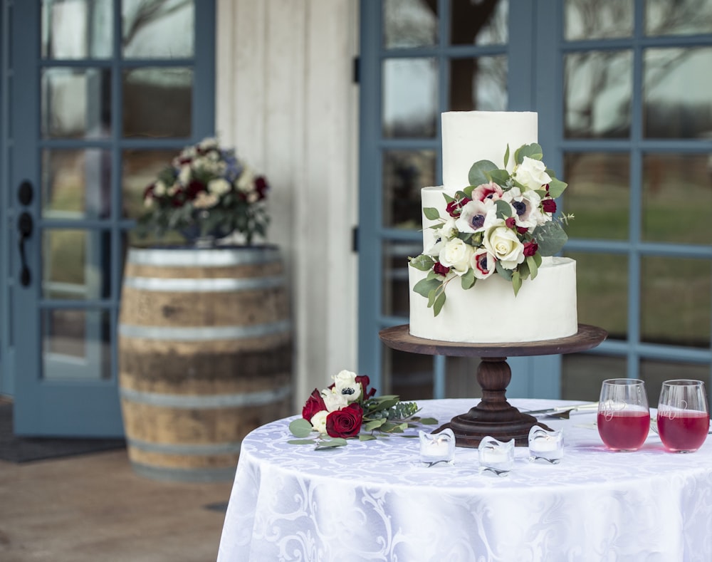 white and pink floral cake on brown wooden round table