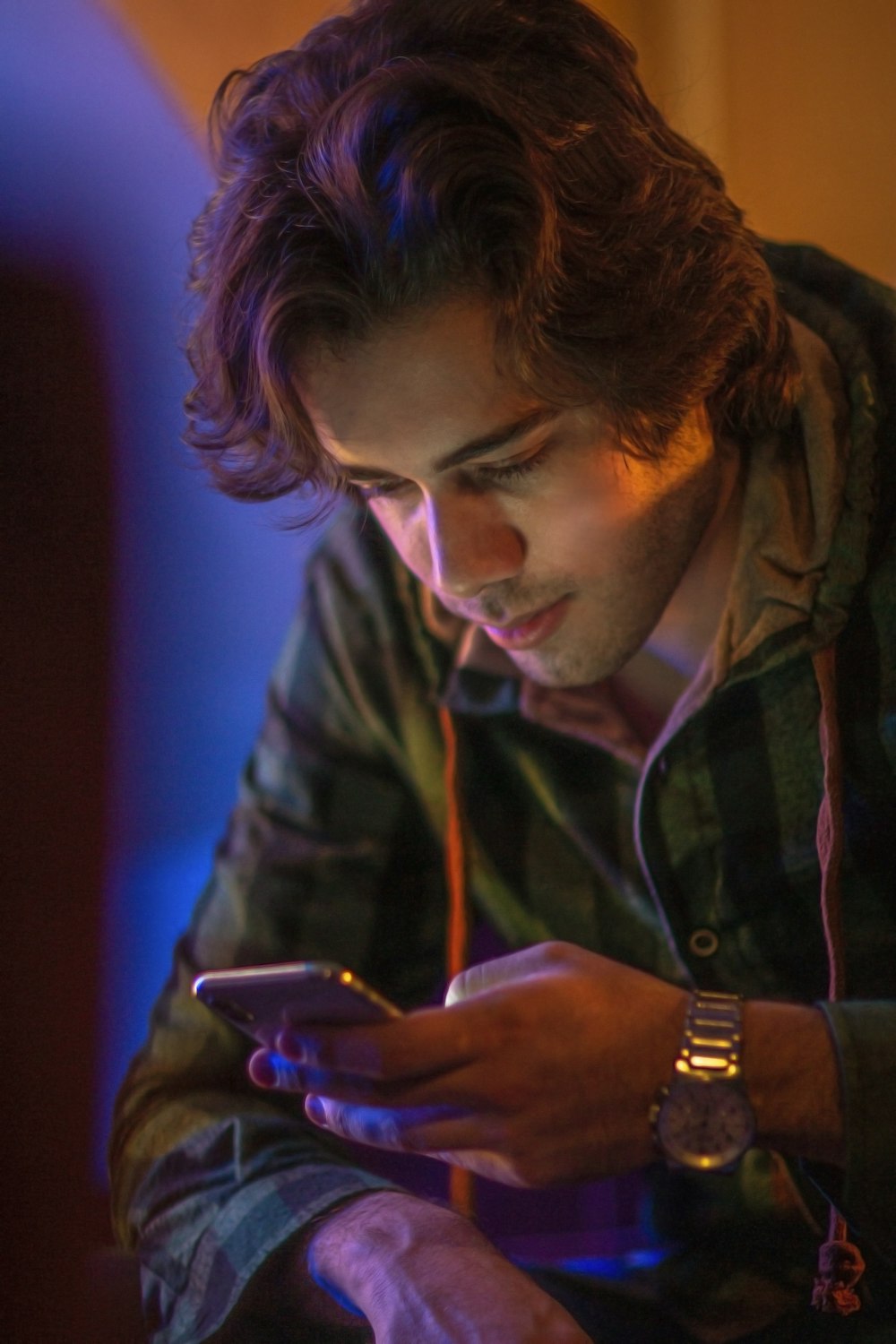 man in brown and black plaid button up shirt using smartphone