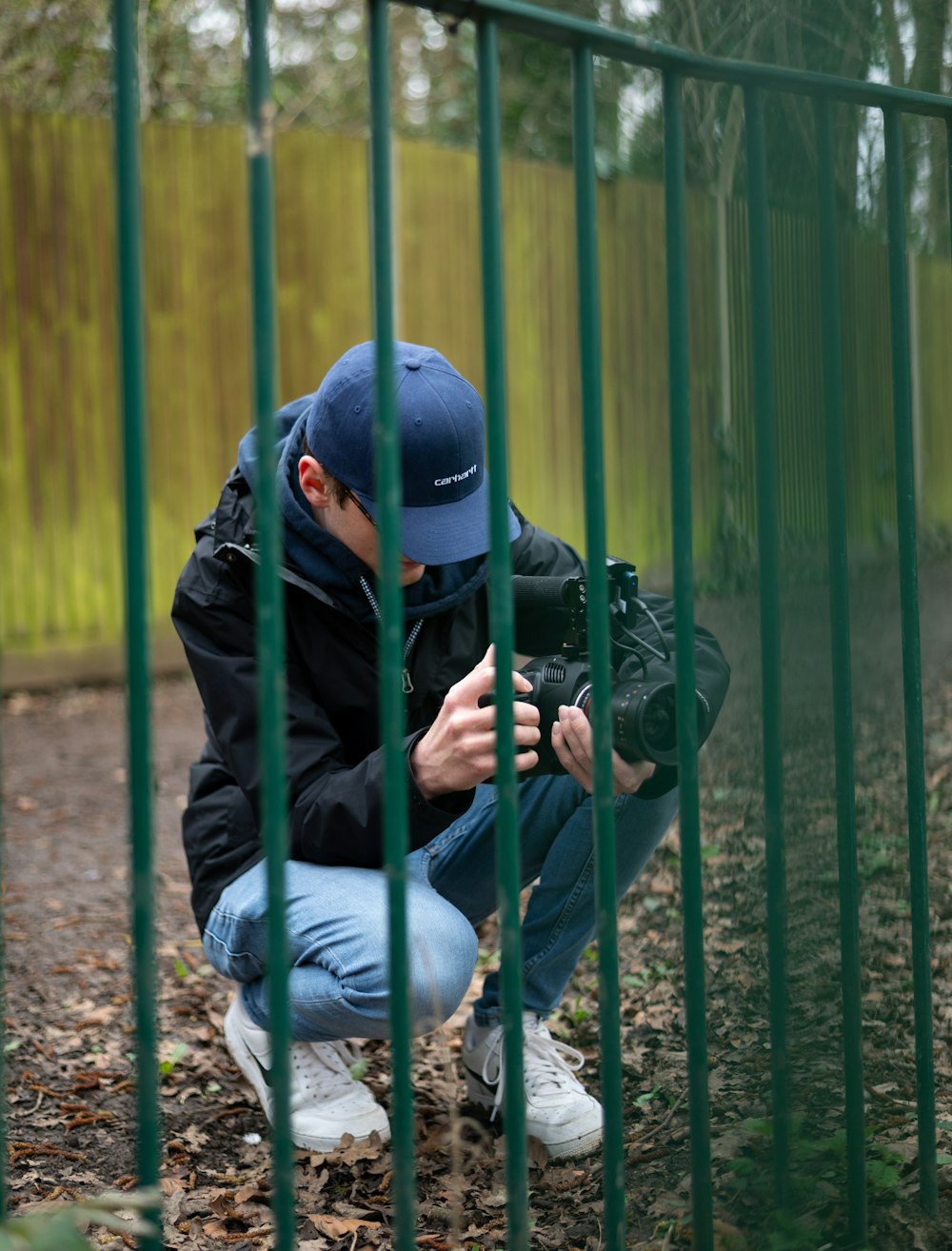 Mann in schwarzer Jacke und blauer Jeans sitzt auf braunem Holzsitz