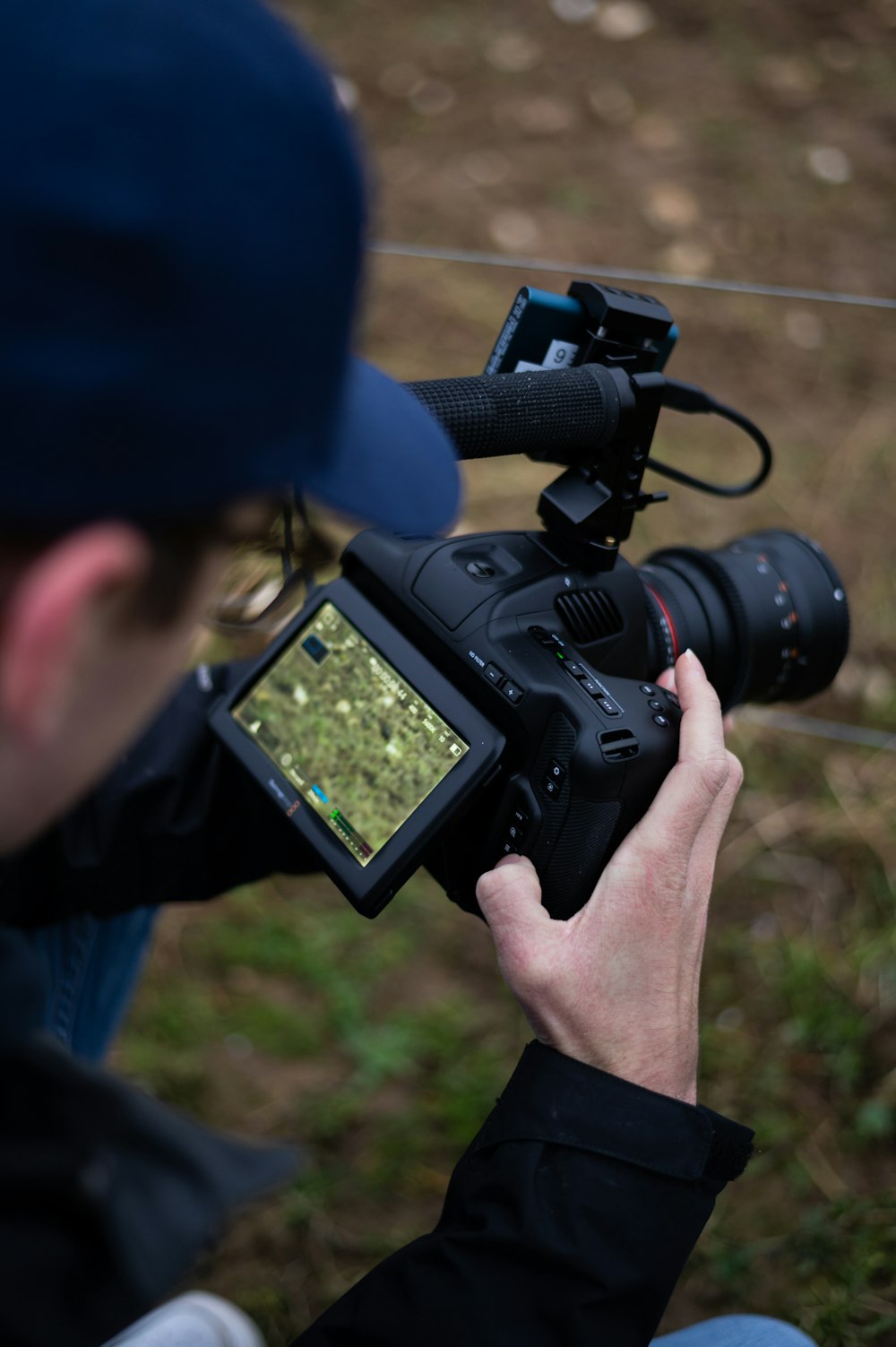 man in blue jacket holding black dslr camera