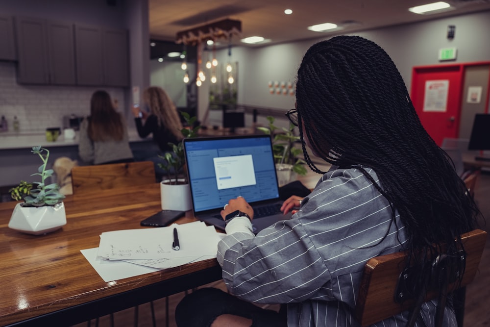 woman in blue and white striped long sleeve shirt using macbook air